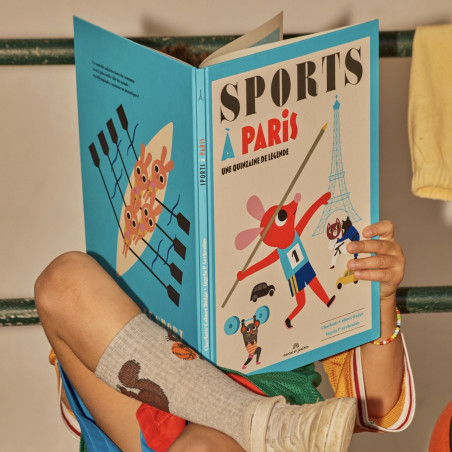 un enfant caché derrière le Livre "Sport à paris" ouvert